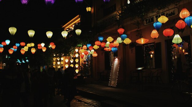 Photo illuminated lanterns hanging on street amidst buildings at night