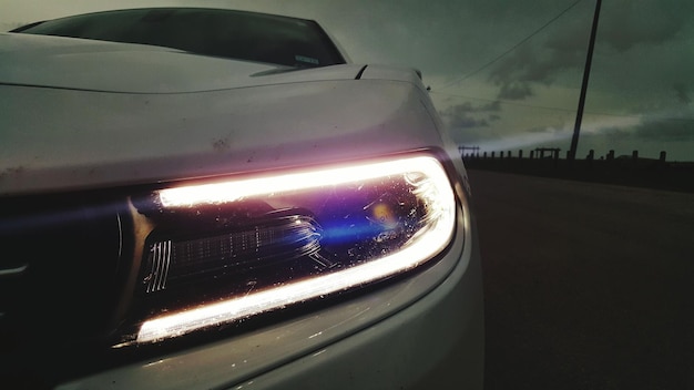 Photo illuminated led headlight on car against sky at dusk