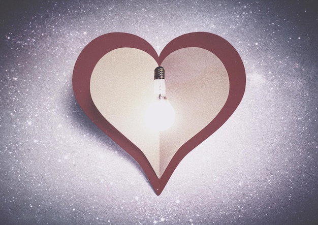Foto lampadina illuminata su carta a forma di cuore