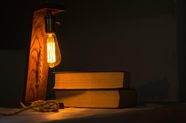 Photo illuminated light bulb on table against wall at night