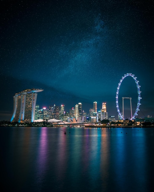 illuminated marina bay sands and buildings with ferris wheel against sky at night