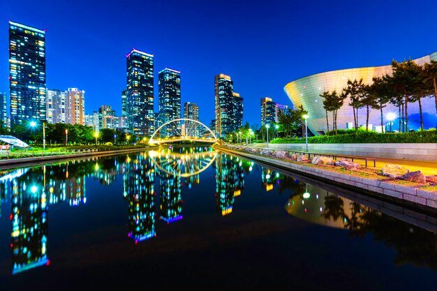 Photo illuminated modern buildings by river against sky at night