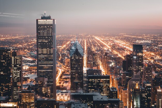 Illuminated modern buildings in city against sky at night