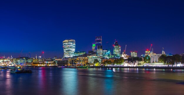 Illuminated modern buildings in city against sky at night