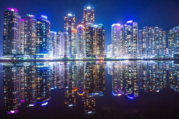 밤 에 물 에 반사 되는 도시 의 조명 된 현대 건물 들