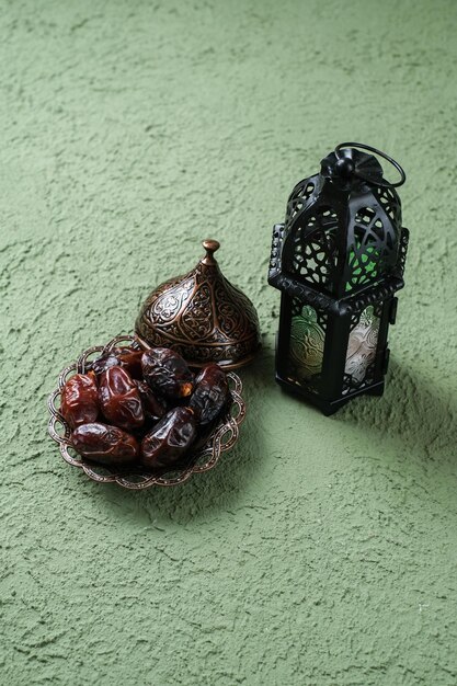 An illuminated Moroccan decorative lamp and dates in an old antique plate Ramadan background concept