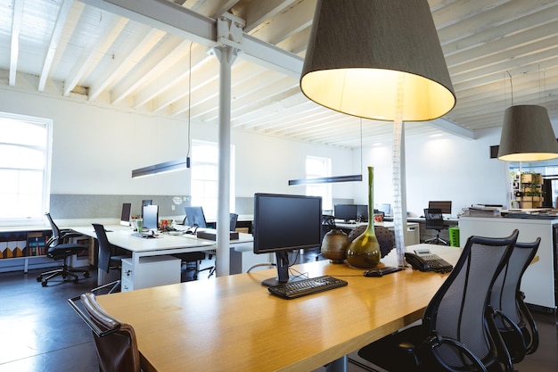 Illuminated pendant light over desk with computers in modern office. unaltered, business, modern office and absence concept.