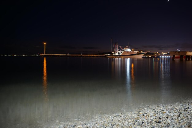 Illuminated pier over sea against sky at night