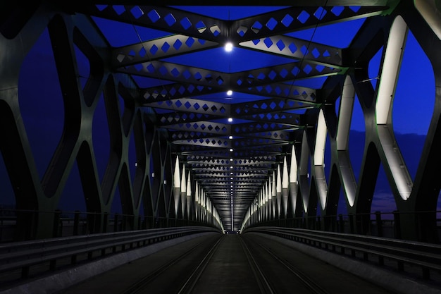Illuminated railroad bridge against blue sky