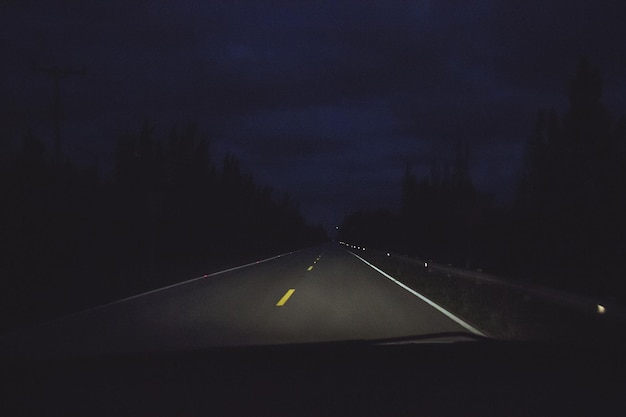 Фото Освещенная дорога на фоне неба, видная из лобового стекла машины ночью