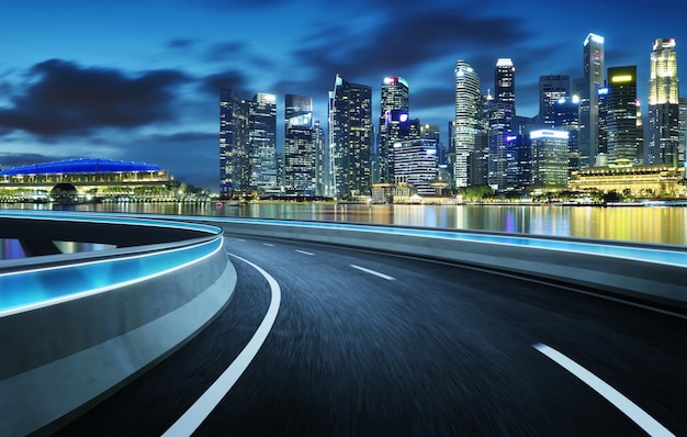 illuminated road by buildings against sky at night