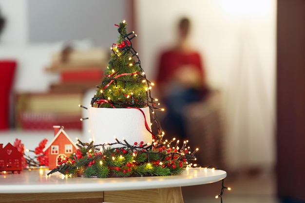 Illuminated small Christmas tree and girl sitting on the background