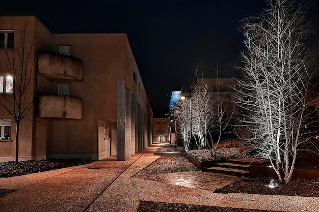 Illuminated street amidst buildings against sky at night