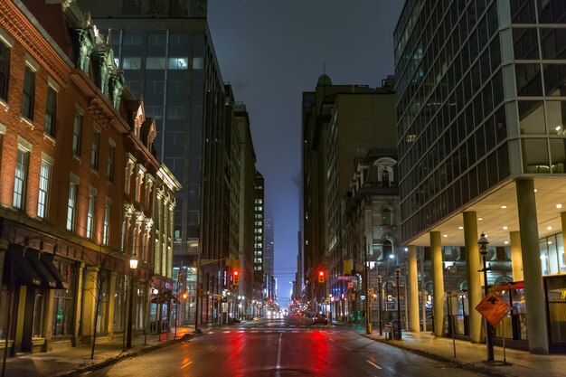 Illuminated street amidst buildings against sky at night