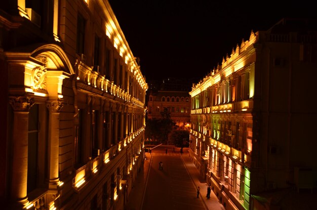 Illuminated street amidst buildings in city at night