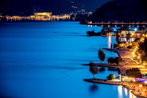 Illuminated street by blue sea at night
