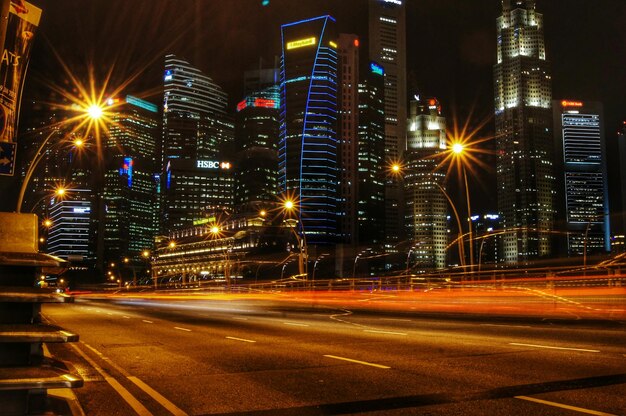 Photo illuminated street by modern buildings in city at night