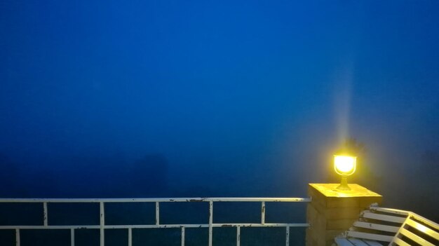 Illuminated street light against blue sky at night