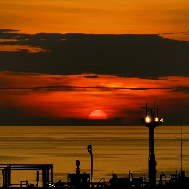 Illuminated street lights against orange sky