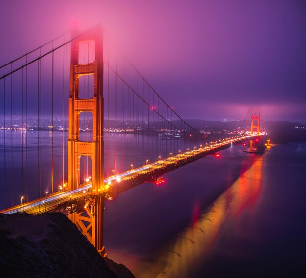 Illuminated suspension bridge over river at night