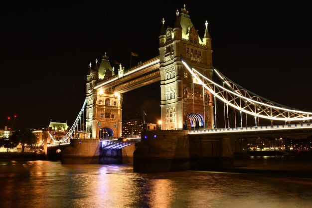 Foto ponte sospeso illuminato sul fiume di notte