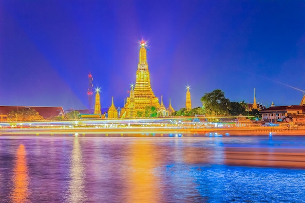 Illuminated temple by building against sky