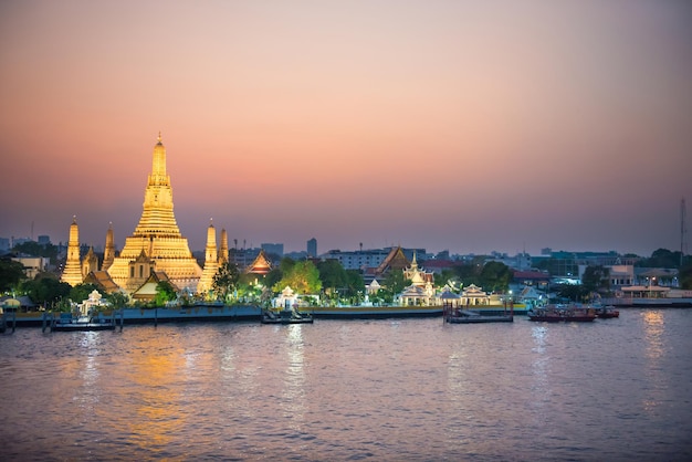 사진 태국 방콕에서 차오프라야 강(chao phraya river)의 조명된 새벽 사원(temple of dawn) 또는 왓 아룬(wat arun)과 톤부리(thonburi) 서쪽 은행