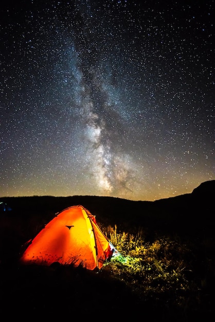 Illuminated tent on field against sky at night