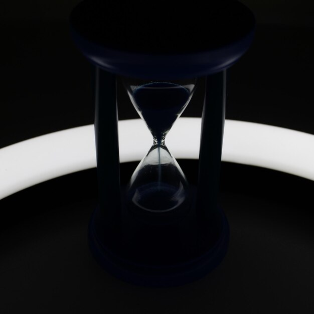 Illuminated Trickle Of Sand Inside Hourglass In Darkness Closeup View