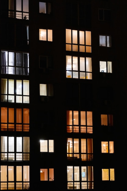 夜の高層マンションのライトアップされた窓 家のライトアップされた夜の窓 都市生活の背景