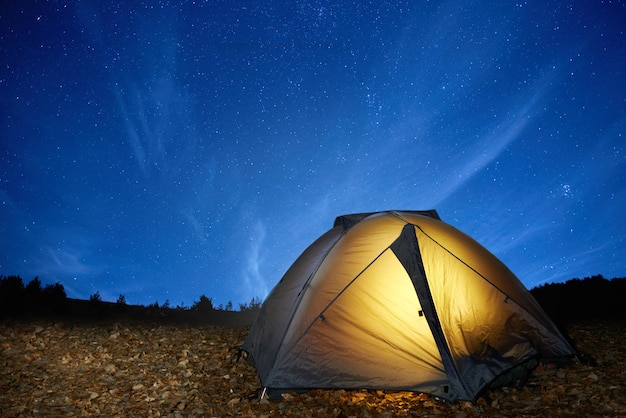 Tenda da campeggio gialla illuminata sotto le stelle di notte