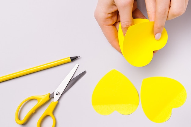 Photo illuminating stickers in the shape of hearts, female hands, pencil and scissors. preparing for valentine's day.