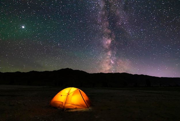 Фото Освещенная палатка под звездами в горах