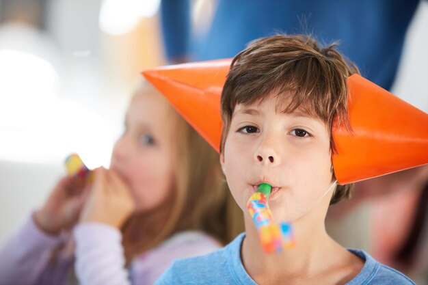 公式パーティーエンターテイナーのIm誕生日パーティーでパーティーホーンで遊んでいるかわいい男の子の肖像画