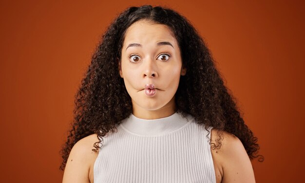 Photo im not saying anything. cropped portrait of an attractive young woman making a face in studio against a red background.