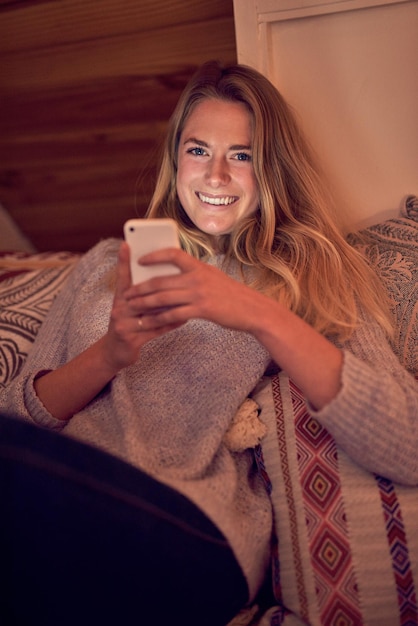 소셜 미디어 마스터 집에서 침실에서 휴식을 취하는 동안 스마트폰으로 문자 메시지를 보내는 젊은 여성의 초상화