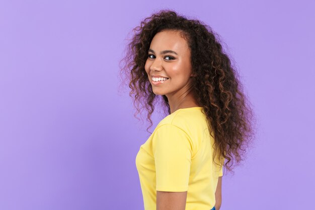 Image of adorable african american woman with curly hair smiling isolated over violet wall