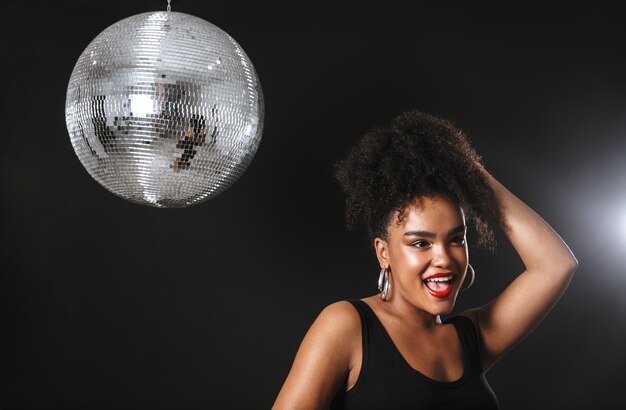 Image of adorable african woman standing with silver disco ball