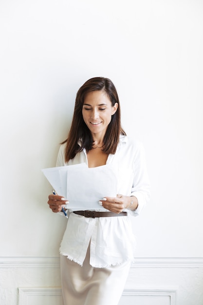 Image of amazing cheery young business woman in office isolated over white wall indoors work with documents.