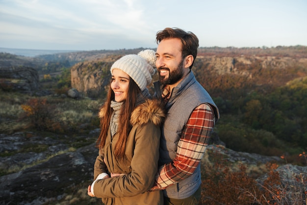 Image of amazing emotional happy young loving couple hugging outside in free alternative vacation camping over mountains.