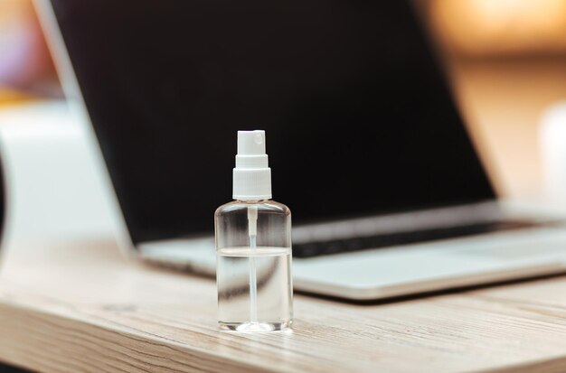 Image of an antiseptic spray next to a laptop on the table