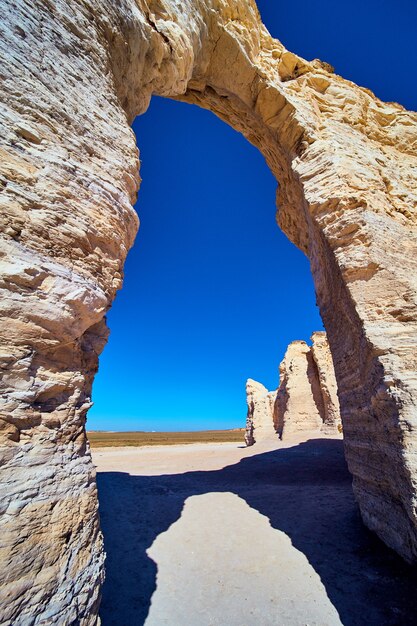image of arch through white stone in desert with blue sky
