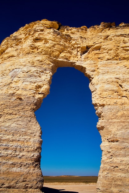 image of archway cutting through natural stone wall with bold blue sky gradient