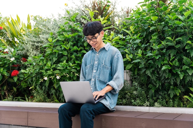 Image of asian boy sitting and using computer in school campus