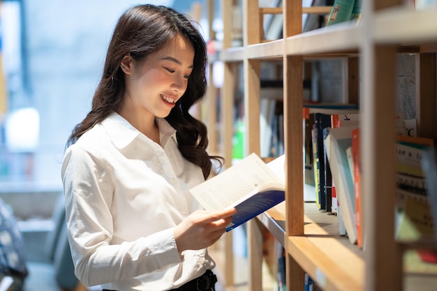 Image of asian businesswoman reading book in library