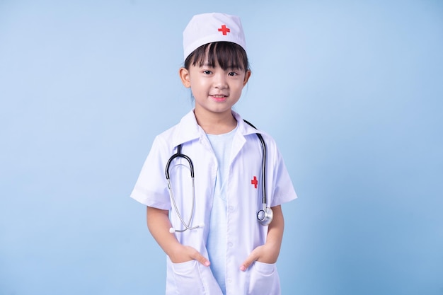 Image of Asian child wearing doctor uniform on blue background