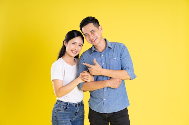 Image of asian couple posing on yellow background