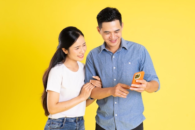 Image of asian couple posing on yellow background