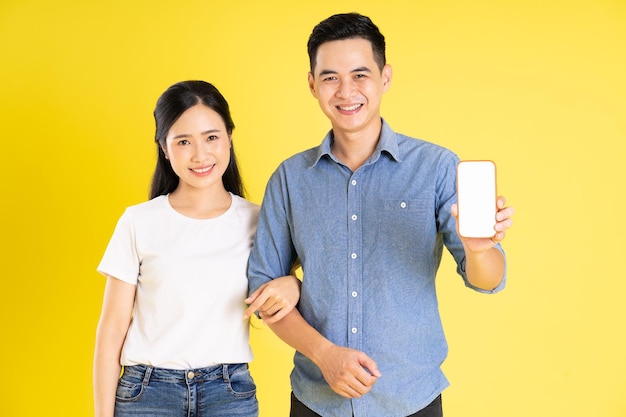 Image of asian couple posing on yellow background