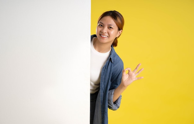 Image of asian female students posing on a yellow background